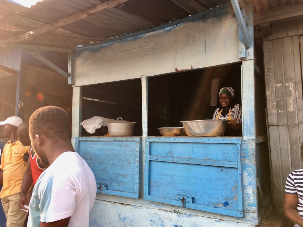 A young girl looks on while men gut and prepare fish at Sekondi fish market